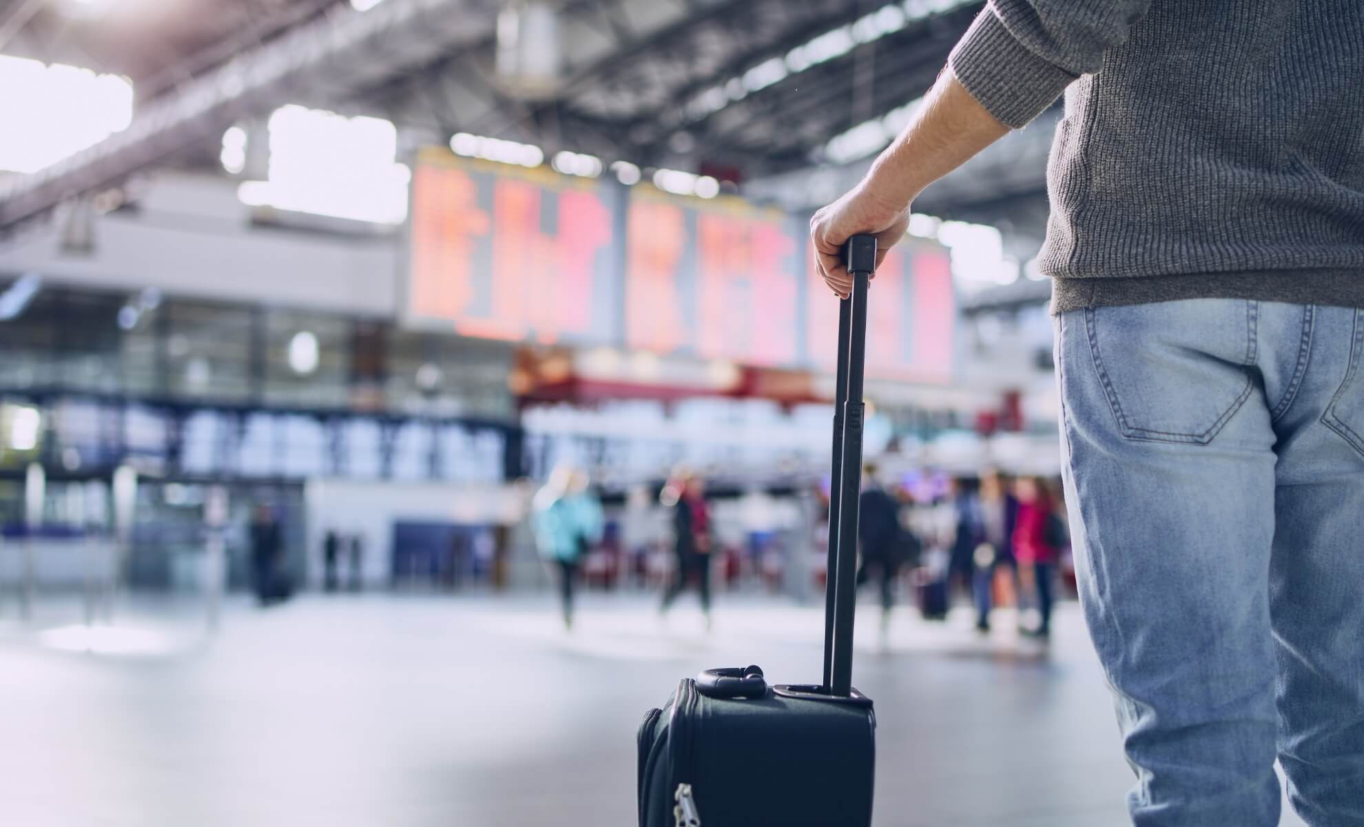 Personne tenant sa valise dans la main au niveau de la gare