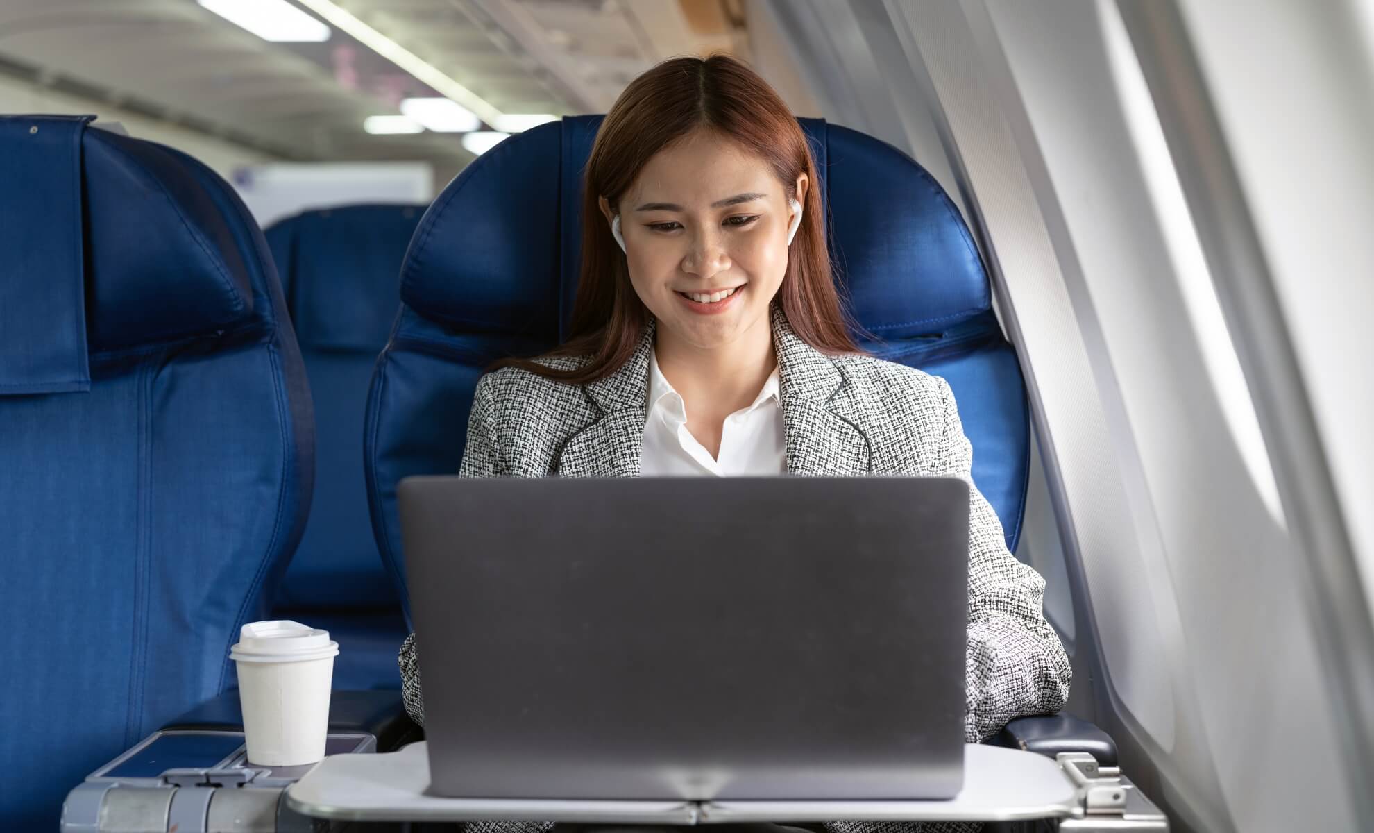 Jeune femme asiatique travaillant sur son PC à bord d'un avion