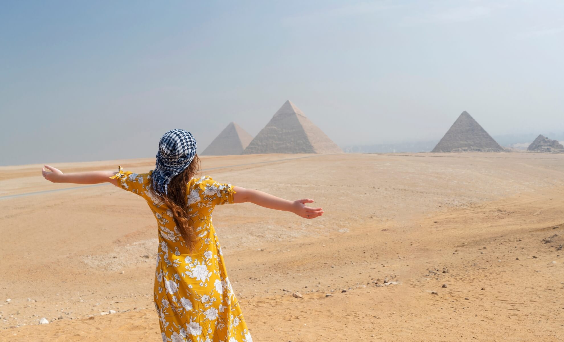 Femme seule dans le Sahara en face de pyramides